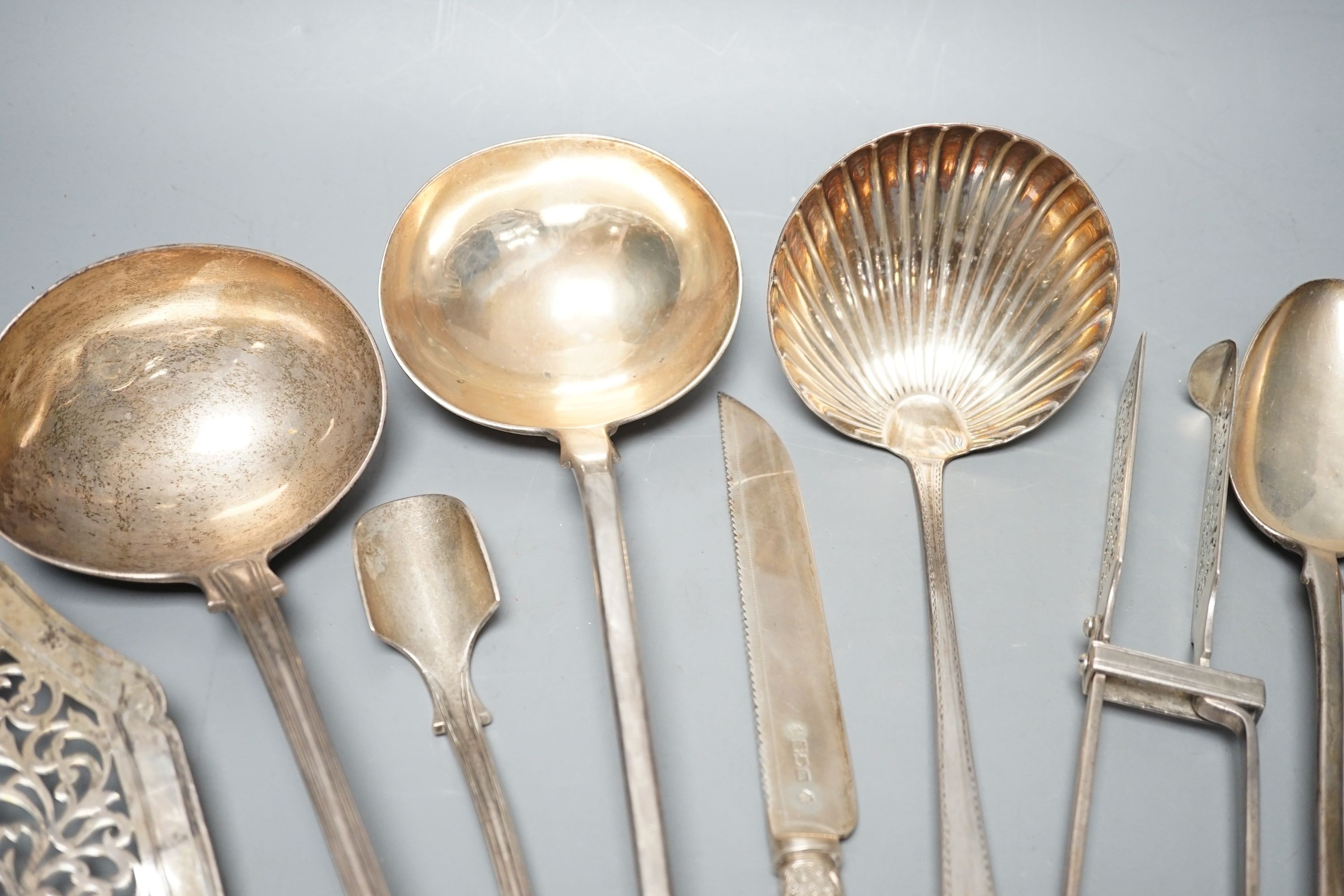 A George III Irish silver Celtic tip soup ladle, Dublin, 1789, A Georgian Irish silver marrow scoop, by William Walsh, two later Victorian silver soup ladles, a pair of Victorian silver asparagus tongs, two silver bastin